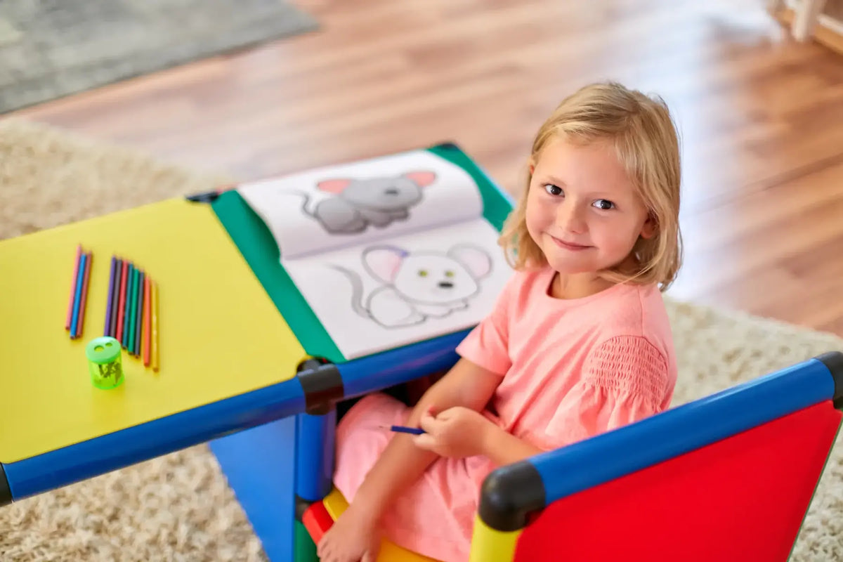 Child drawing at a yellow QUADRO activity table with colourful pencils