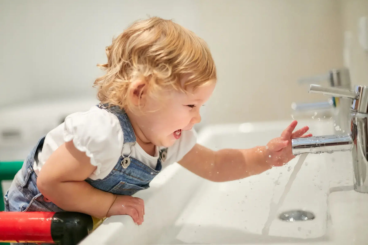 Toddler reaching a running tap from a colourful QUADRO learning tower