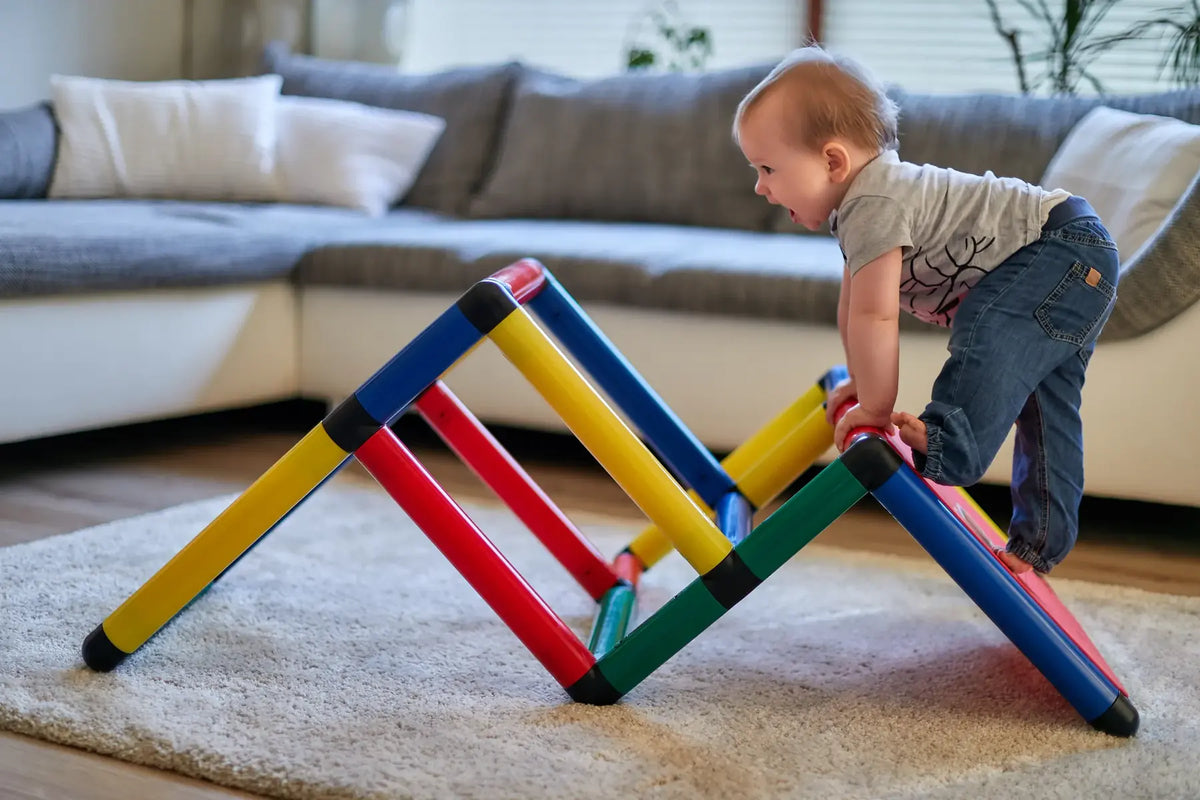 Toddler climbing over a low triangular QUADRO frame in a living room