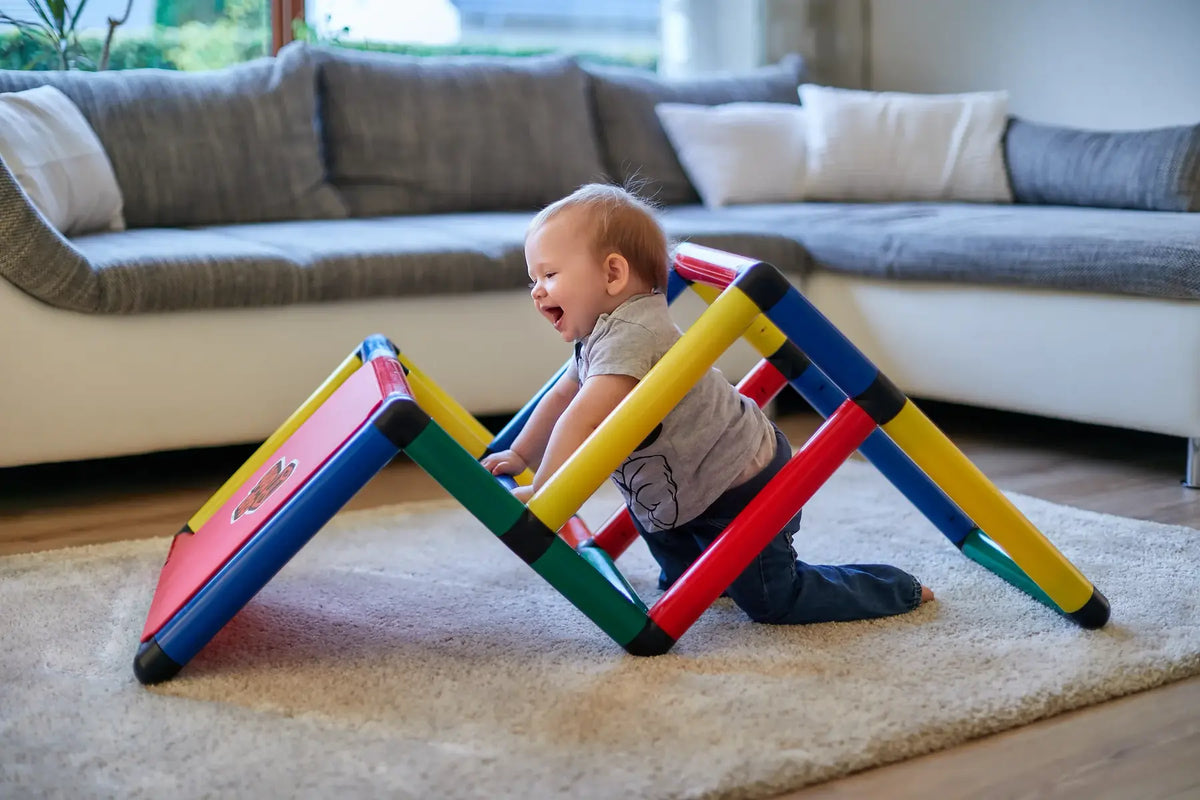 Toddler seated on the sloped panel of a low QUADRO climbing frame
