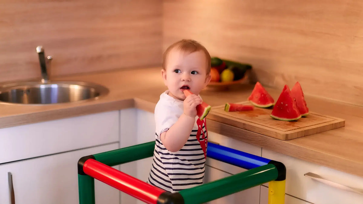 Toddler eating watermelon while standing in a QUADRO learning tower