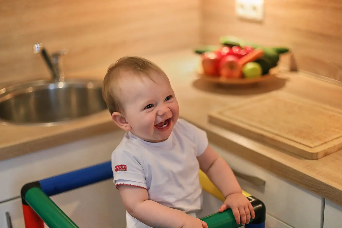 Smiling toddler standing behind the safety rail of a QUADRO learning tower