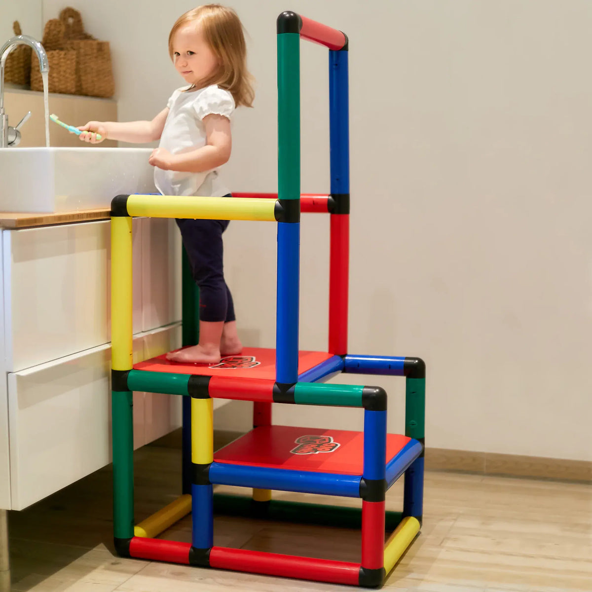 Child using a two-level QUADRO learning tower at a bathroom sink
