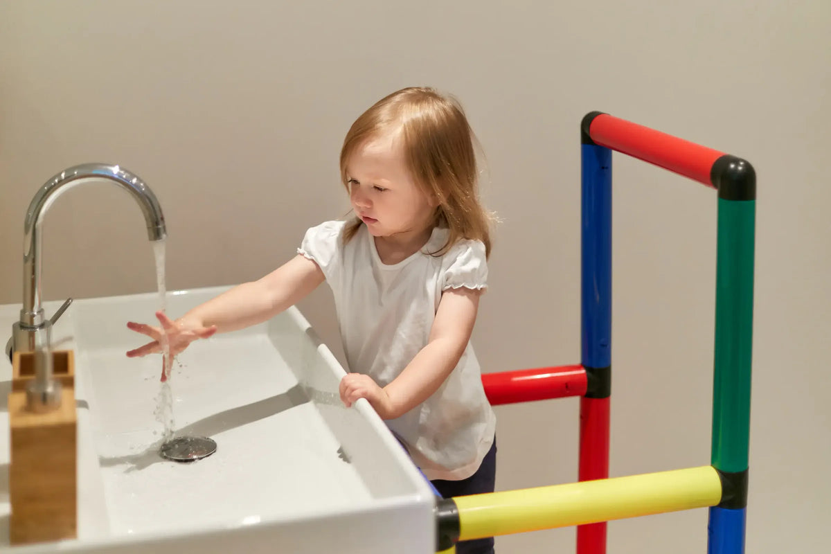 Child reaching the tap from the upper rail of a QUADRO learning tower