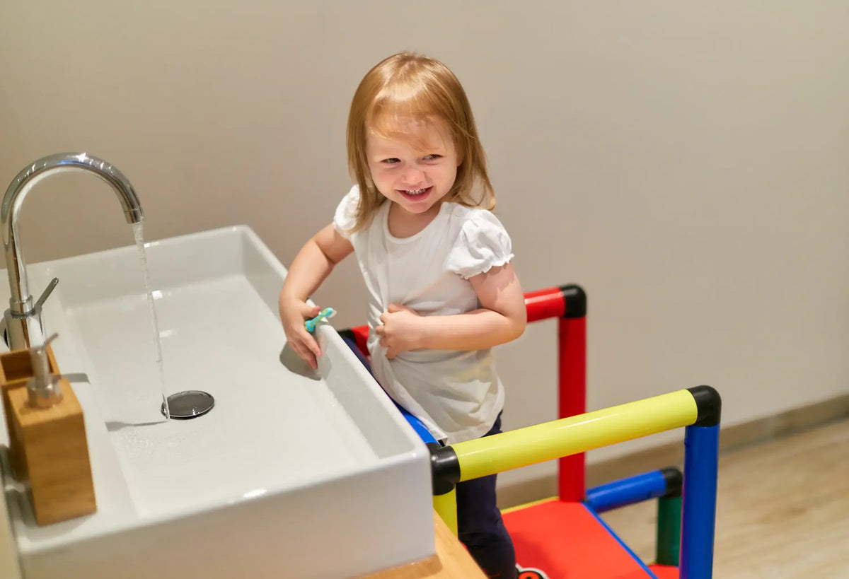 Smiling child beside a sink inside the safety rails of a QUADRO tower