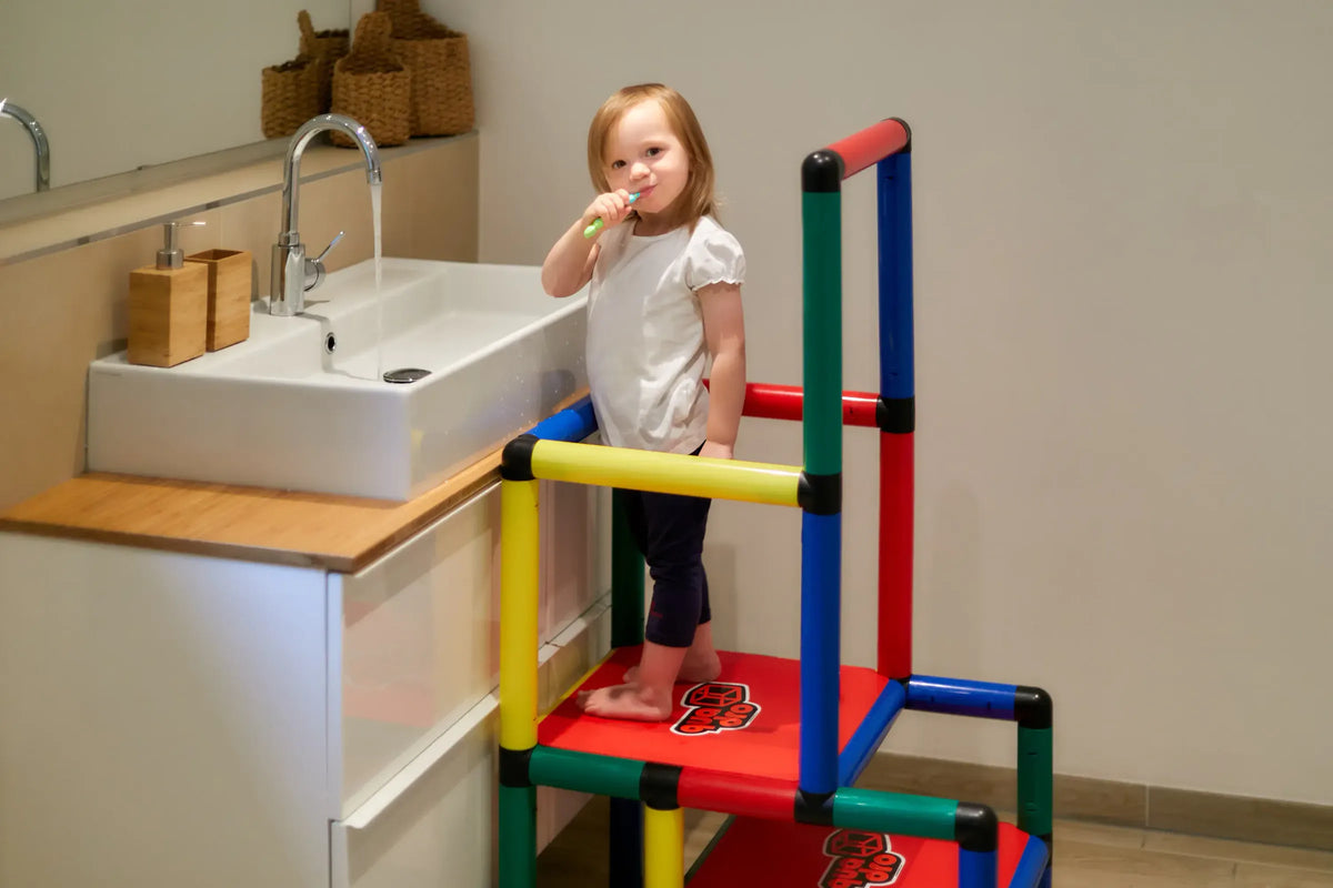 Child brushing teeth while standing on a two-level QUADRO learning tower