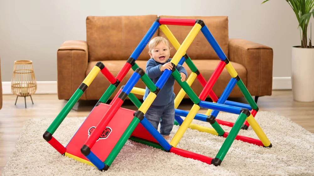 Toddler climbing through a colourful indoor QUADRO pyramid with ramp