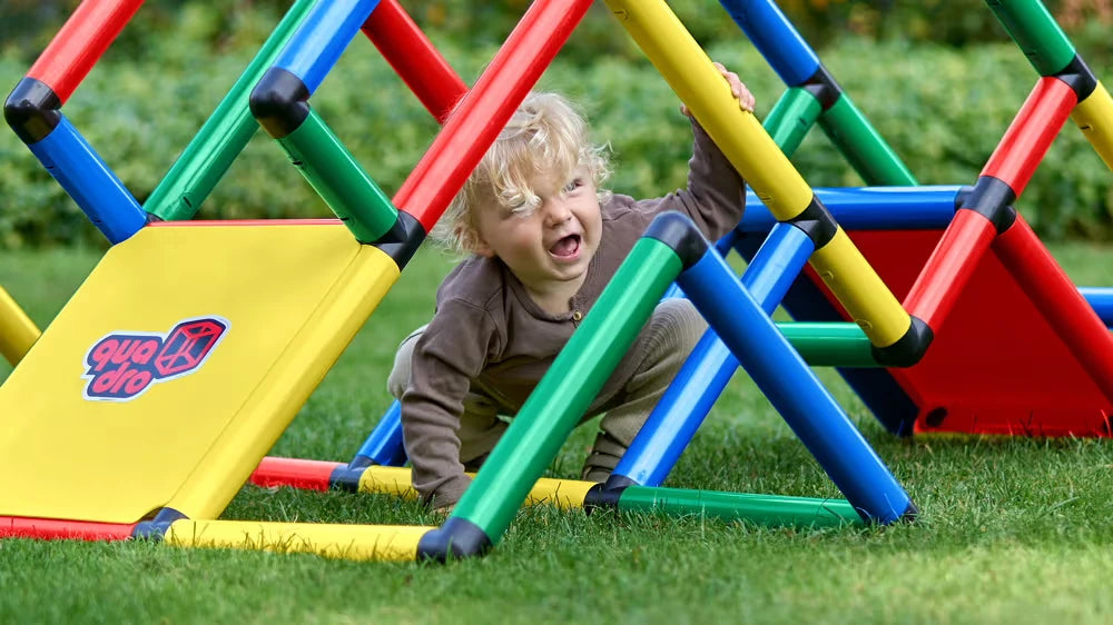Child crawling beneath a colourful QUADRO climbing frame on grass