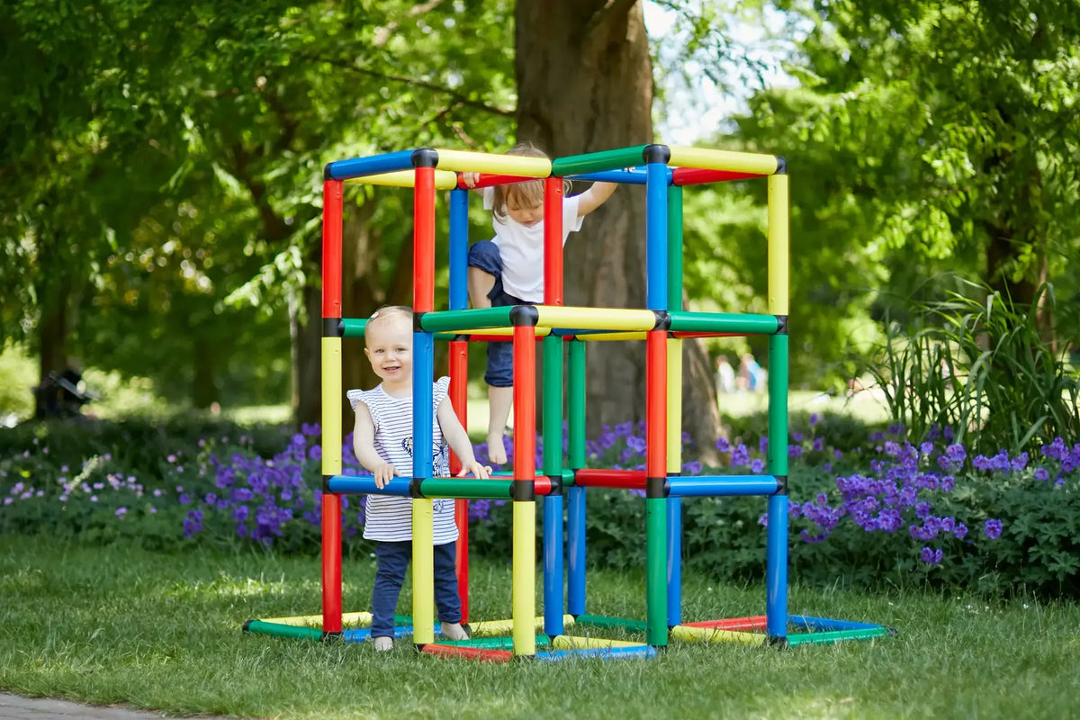 Two children climbing a tall multicoloured QUADRO cube tower outdoors
