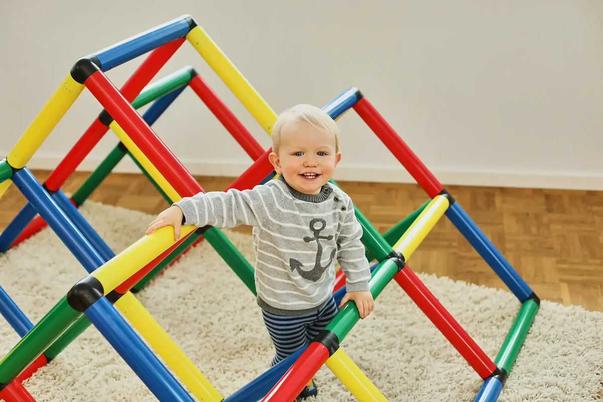 Toddler standing inside a low angular QUADRO climbing pyramid indoors