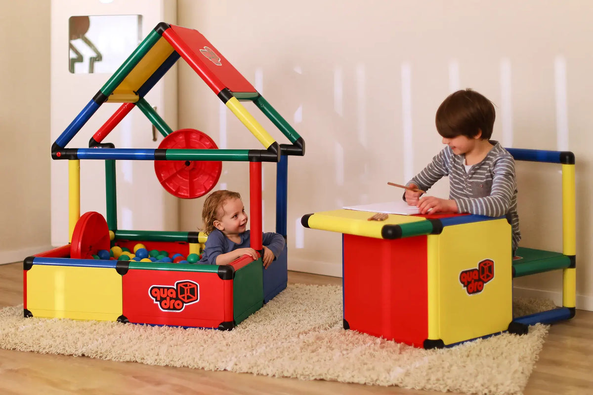 Two children playing in a QUADRO Evolution house and at a small table