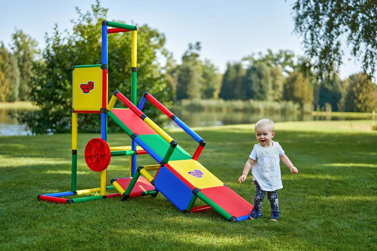 Toddler beside a QUADRO Evolution tower with ramp and red wheel outdoors