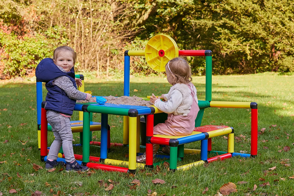 Two toddlers playing at a large outdoor QUADRO table with bench seats