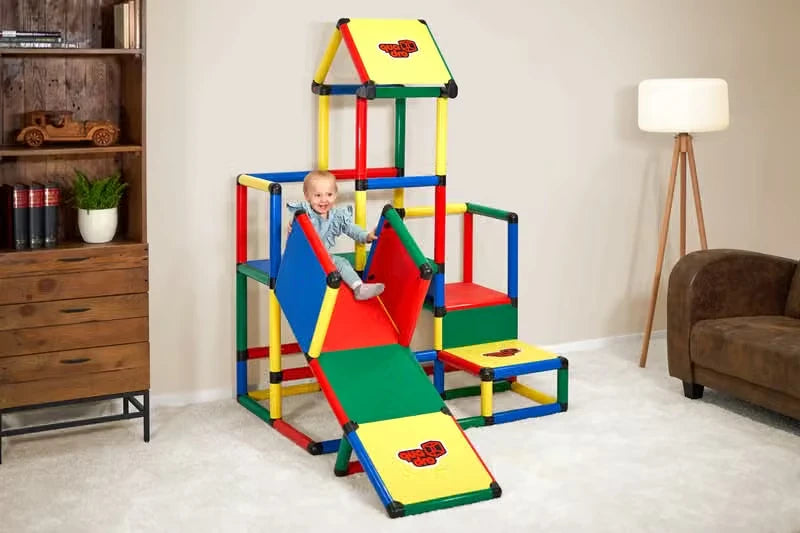 Toddler seated on the ramp of an indoor QUADRO climbing tower with roof
